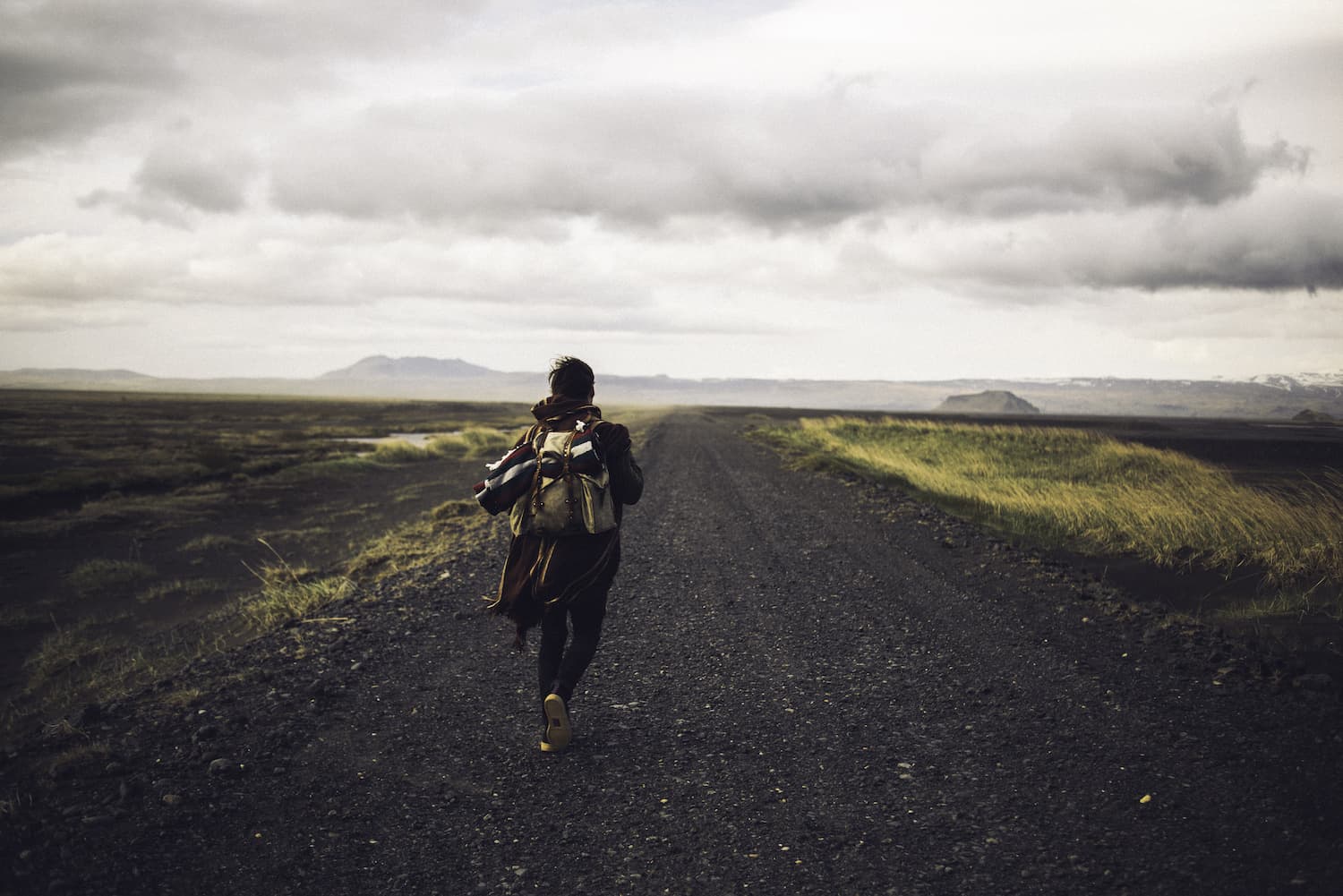 Caminante solitario en un camino abierto bajo cielo nublado